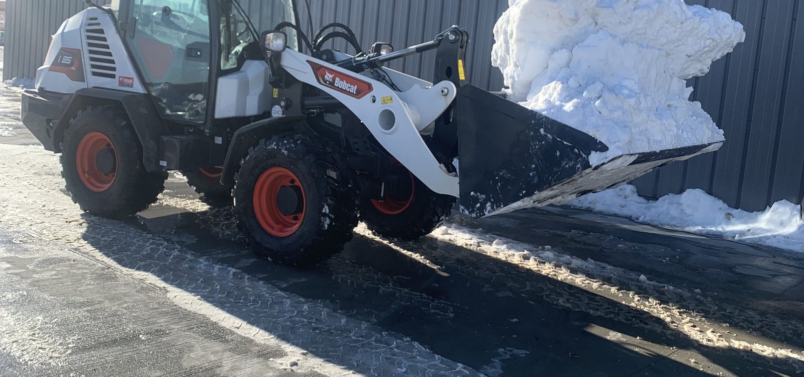 Stormworthy wheel loader carrying snow off a commercial property in Bismarck, ND