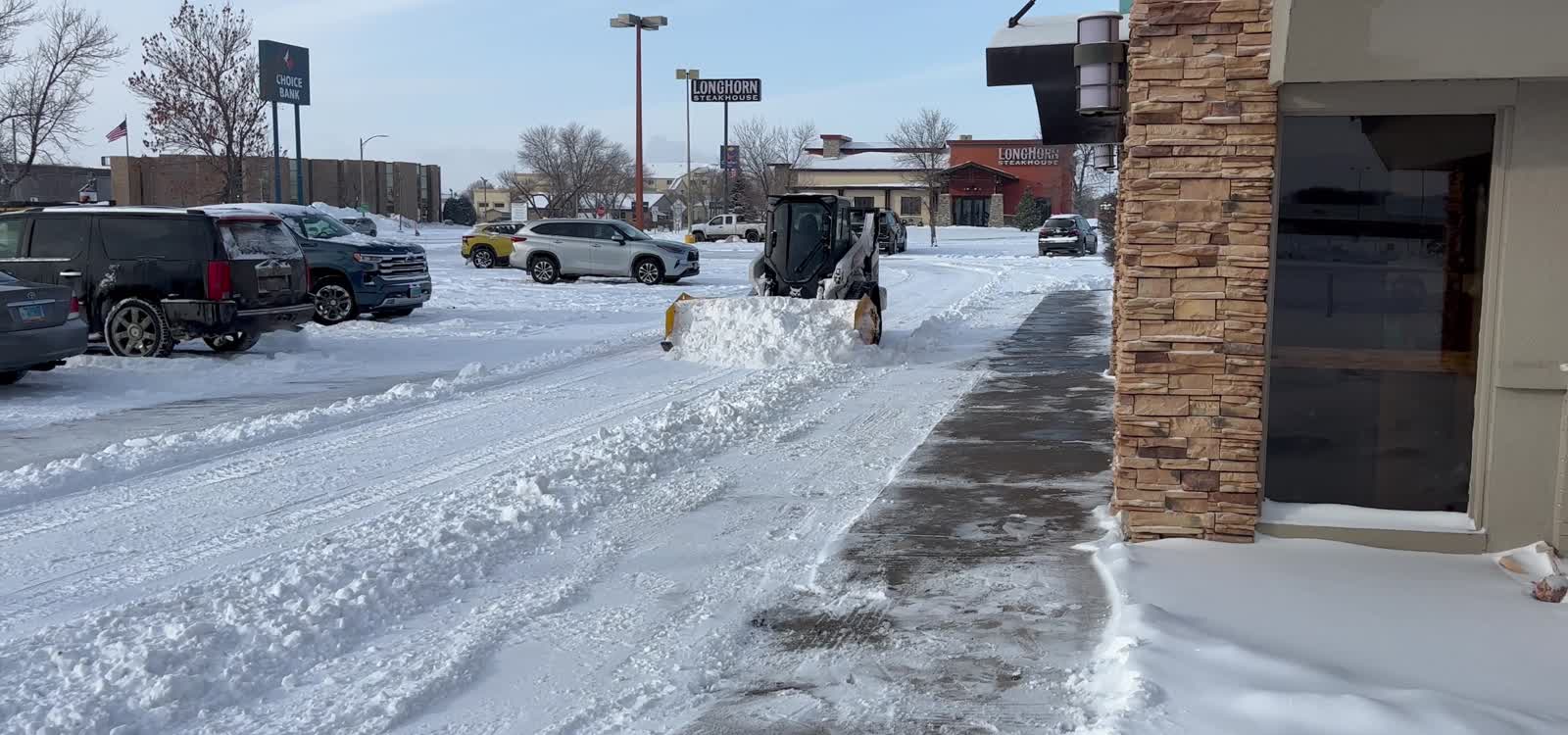 Stormworthy track loader and sectional pusher clearing snow from a commercial parking lot in Bismarck, ND
